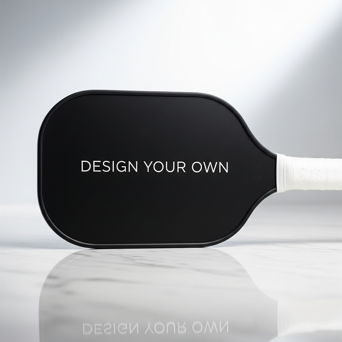 Black paddle with 'Design Your Own' text on a reflective surface.