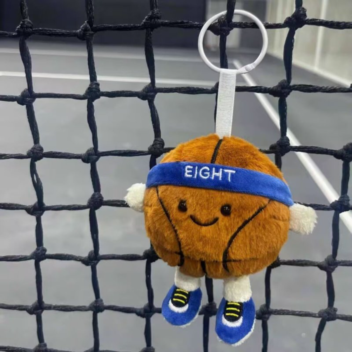 Plush basketball keychain with a blue headband labeled 'EIGHT' hanging on a net.