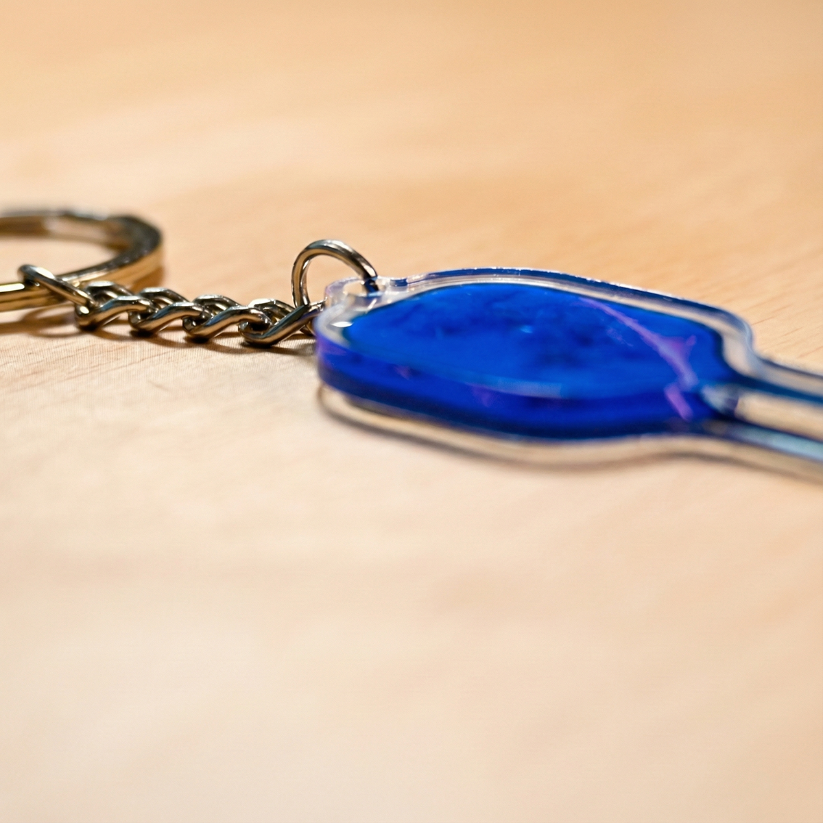 Blue keychain with a metal ring on a beige background