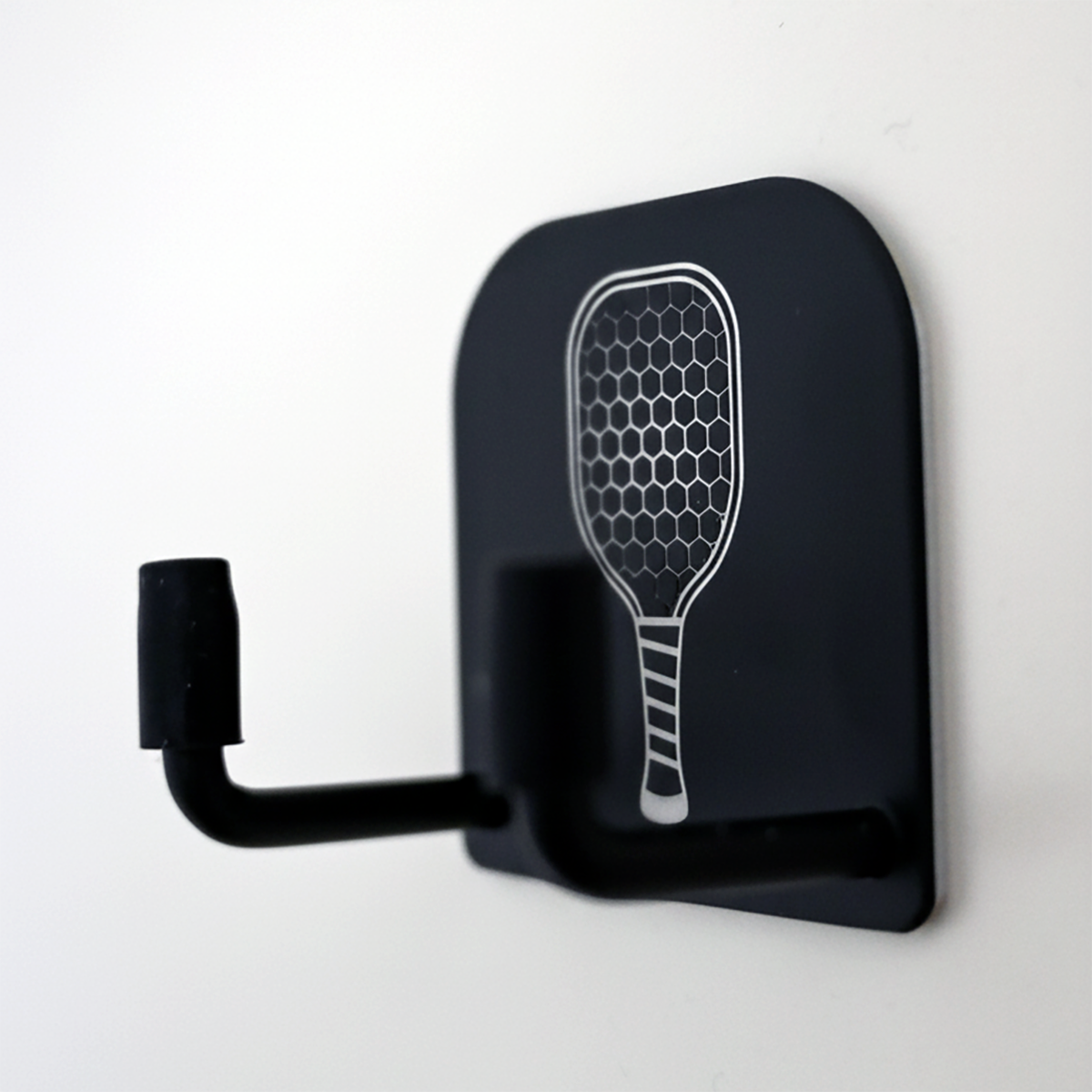 Black wall hook with paddle design on a white background